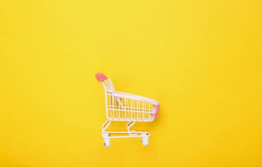 Sarı arka planda boş Mini süpermarket arabası