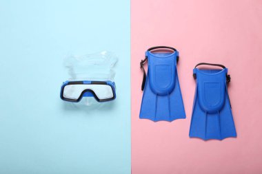 Dalış maskesi ve mavi pastel arka planda yüzgeçler. Seyahat konsepti, deniz tatili. Minimalist fotoğraf. Düz yatış, üst görünüm