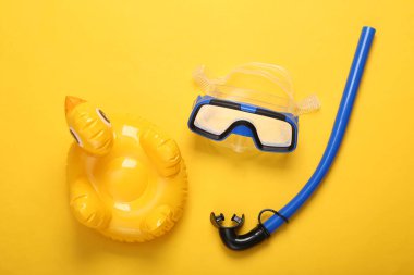 Dalış maskesi ve şnorkel, sarı arka planda şişme ördek. Üst görünüm