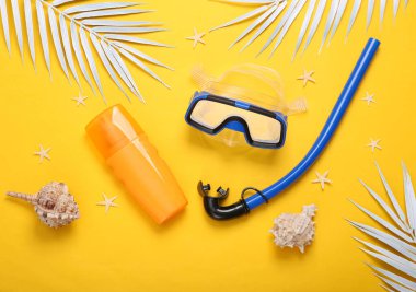 Yaz sahili geçmişi. Dalış şnorkeli ve maske, güneş kremi şişesi, deniz kabukları, palmiye yaprakları ve sarı arka planda deniz yıldızları. Üst görünüm