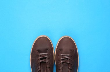 Mavi arka planda erkek kahverengi deri ayakkabılar. Üst görünüm