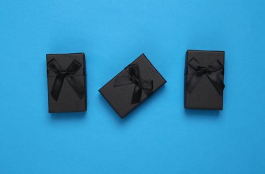 Mavi arka planda siyah hediye kutuları. Üst görünüm