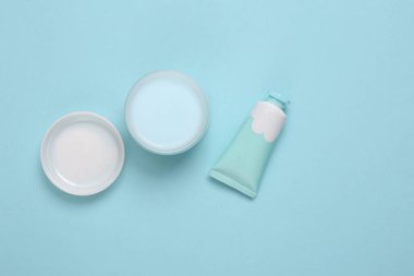 Mavi arka planda kavanoz ve bir tüp krema. Üst görünüm