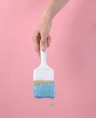 Pembe arka planda damlayan turkuaz boyalı el fırçası. Asgari yaratıcı düzen. Sanat kavramı.