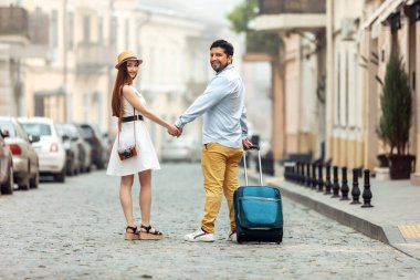 Ortak, romantik bir gezi. Seyahat valizli uluslararası turistleri seven bir çift Avrupa caddesi boyunca yürüyorlar. Birlikte vakit geçirin..