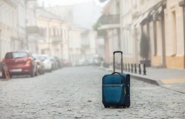 Boş bir Avrupa caddesinin ortasında seyahat bagajı. Turizm, Seyahat konsepti