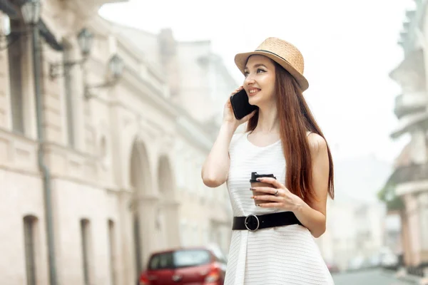 모자를 귀여운 코카서스 전화로 이야기하고 도시에서 커피를 마시는 — 스톡 사진