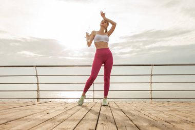 Spor giyim ve plajda su şişesi olan güzel bir fitness modeli.