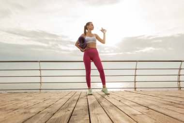 Formda bir kadın sahilde su içer. Sağlıklı yaşam tarzı