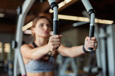 Spor kıyafetleri içinde güzel bir kadın egzersiz makinesinde göğüs kaslarını çalıştırıyor. Sağlıklı bir yaşam tarzı. Güçlü vücut