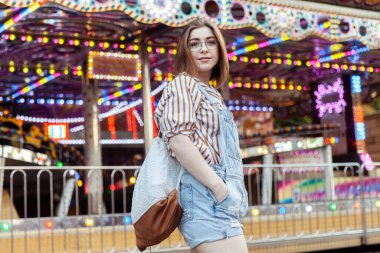 Kot pantolon giymiş, eğlence parkında gözlüklü, şık bir kadın.