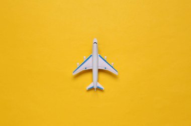 Sarı arka planda oyuncak yolcu uçağı. Yolculuk, seyahat konsepti. Üst görünüm