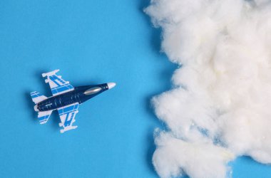 Mavi arka planda bulutlu oyuncak savaş uçağı