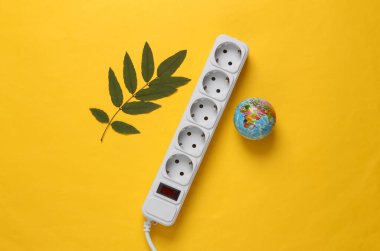 Gezegeni kurtar. Elektrik uzatma kablosu, küre ve sarı arka planda yeşil yapraklar. Yeşil enerji. Üst Manzara. Düz yatıyordu
