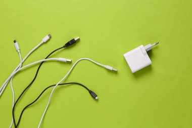 Yeşil arka planda farklı usb kablosu ve şarj aleti. Eko konsepti. Üst görünüm