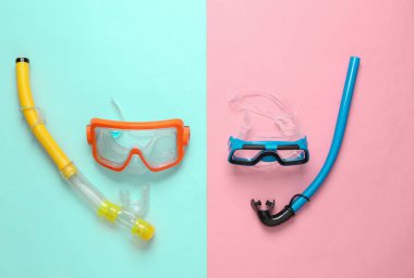 Yetişkin ve çocuk dalış maskesi ve mavi pembe arka planda şnorkel.