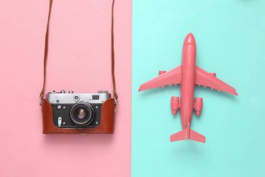 Deri kaplı bir Retro kamera ve pembe mavi arka planda bir uçak. Seyahat konsepti. Düz yatıyordu. Üst görünüm