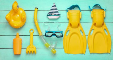 Dalış takımı ve plaj aksesuarları mavi ahşap bir arka planda. Üst görünüm