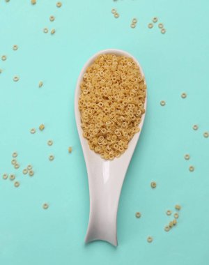 Mavi arka planda makarnalı seramik kaşık. Üst görünüm