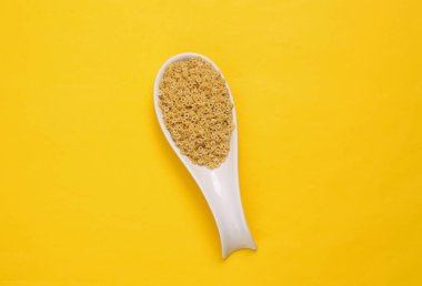 Sarı zemin üzerinde makarna olan seramik kaşık. Üst görünüm