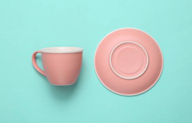 Mavi arka planda boş fincan ve çay tabağı. Üst görünüm