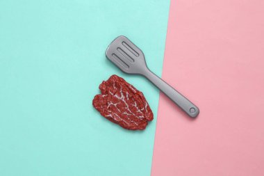 Mavi-pembe pastel arka planda plastik et ve çatal. Üst Manzara. En az gıda konsepti