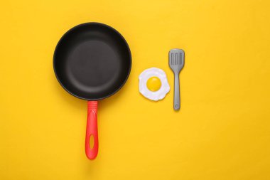Sarı arka planda plastik yumurta, tava ve çatal. Üst Manzara. En az gıda konsepti