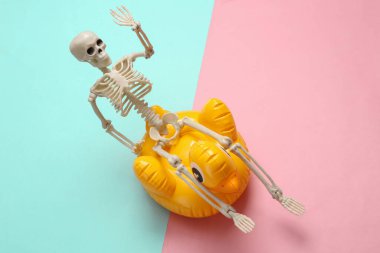 Sarı arka planda şişme ördek olan iskelet. Minimum yerleşim, Cadılar Bayramı partisi, yaratıcı düzen