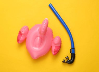 Sarı arka planda şnorkeli olan şişme flamingo. Minimum yaz konsepti. Üst görünüm.