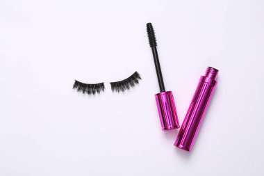 Sahte kirpikler ve beyaz arka planda rimel sürmüş kirpik fırçası. Yaratıcı düz yatak, güzellik konsepti