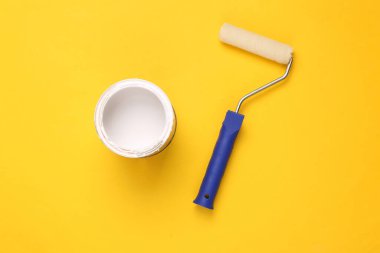 Boya silindiri ve sarı arka planda beyaz boya. Üst Manzara. Ev yenileme konsepti 