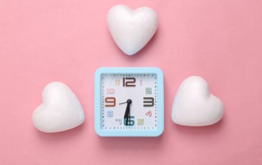 Pembe arka planda kalpleri olan çalar saat. Romantik, aşk konsepti, Sevgililer Günü