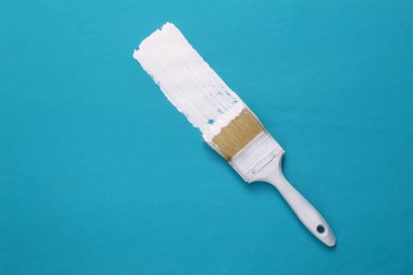 Fırça mavi arka planda beyaz bir boya şeridi çizer