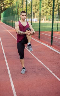 Atletik kaslı adam antrenmandan önce stadyumda ısınıyor. Sağlıklı yaşam tarzı