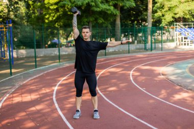 Stadyumda bir dambıl ile atletik erkek antrenmanı