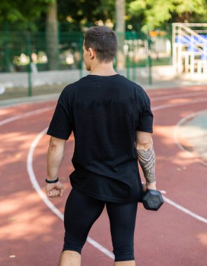 Stadyumda bir dambıl ile atletik erkek antrenmanı