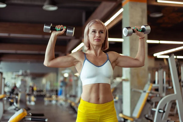 근육질의 여자는 현대의 체육관에서 군침으로 근육을 시킨다 아름다운 — 스톡 사진