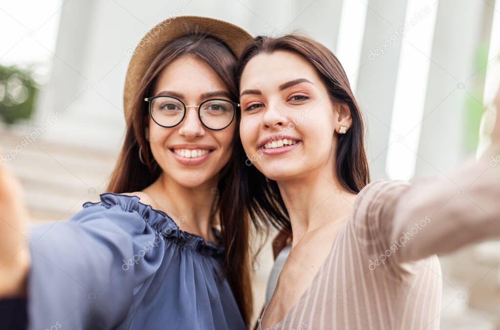 Two young women take a selfie together and have fun in the city.