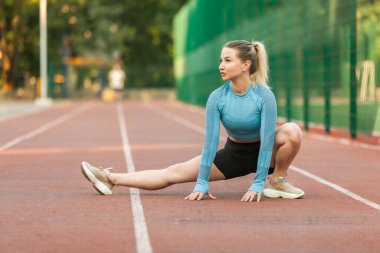 Atletik kadın stadyumda antrenmandan önce ısınıyor. Sağlıklı yaşam tarzı