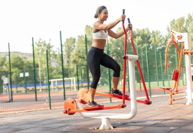 Genç atletik kadın dışarıda egzersiz malzemeleriyle antrenman yapıyor.