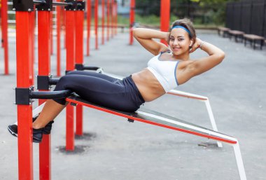 Modern spor sahalarında karın kaslarını çalıştıran güzel atletik bir kadın.