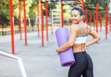 Egzersiz sahasında paspası olan güzel, güler yüzlü, formda bir kadın.