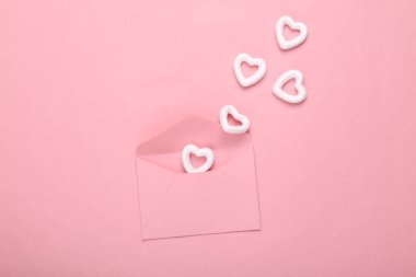 Pembe zemin üzerinde beyaz kalpler olan zarf. Yaratıcı düzen. Aşk konsepti, Sevgililer günün kutlu olsun.