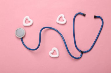 Pembe arka planda kalpleri olan steteskop. Kalp terapisi, aşk konsepti