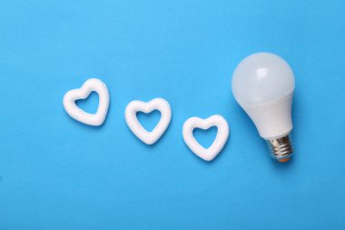 Mavi arka planda beyaz kalpli bir ampul. Yaratıcı düzen. Aşk konsepti, Sevgililer günün kutlu olsun.