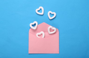 Mavi zemin üzerinde beyaz kalpler olan zarf. Yaratıcı düzen. Aşk konsepti, Sevgililer günün kutlu olsun.