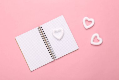 Pembe arka planda kalpleri olan bir not defteri. Günlük, aşk mektupları, aşk mucizesi, Sevgililer Günü