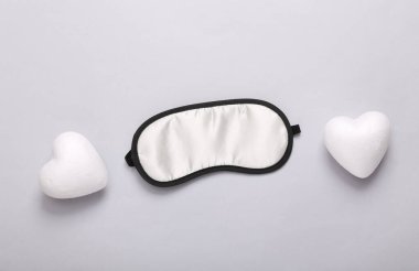 Tatlı rüyalar konsepti. Gri arka planda uyuyan maske ve kalpler. Üst Manzara. Asgari biçim