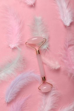 Pembe arka planda yüz silindiri ve yumuşak renkli tüyler. Güzellik konsepti