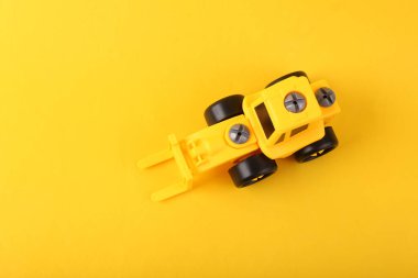 Sarı arka planda oyuncak sarı forklift. Üst görünüm